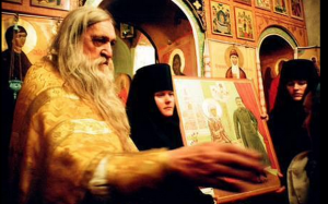 A Russian Orthodox priest is holding a holy image with Stalin in it